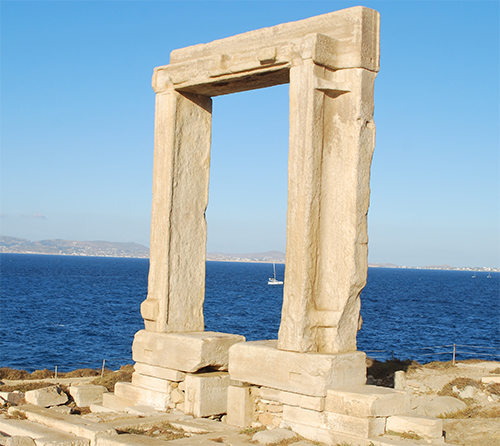 Una antigua puerta de piedra rectangular se encuentra en ruinas junto al mar bajo un cielo despejado.

Descripción generada con IA