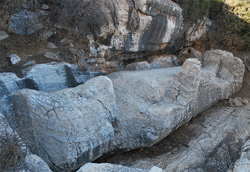 Una escultura de piedra grande con forma de sofá está tallada en un entorno rocoso al aire libre.

Descripción generada con IA