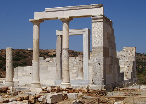 Ruinas antiguas de piedra con columnas y un marco rectangular en un paisaje árido bajo un cielo despejado.

Descripción generada con IA
